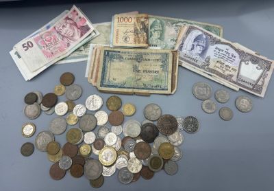 une pile de billets et de pièces posée sur une table à côté d'un ordinateur portable