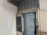 four en acier inoxydable dans une cuisine professionnelle dont les murs sont recouverts de carrelage blanc