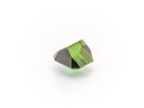 a close up of a green and black diamond on a white surface