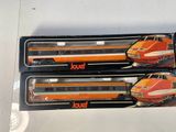 two orange and white train cars sitting on top of a white table