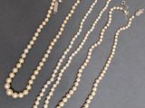 trois colliers de perles et une paire de boucles d'oreilles posés sur une table