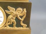a gold clock with a picture of a winged angel on it