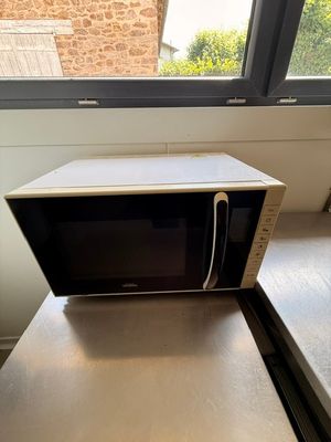 un micro-ondes posé sur une table près d'une fenêtre