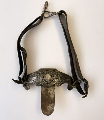 un couteau accroché au mur, maintenu par une lanière en cuir
