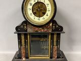 une horloge noire et dorée posée sur un socle en marbre