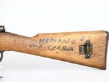 an old wooden rifle with writing on it sitting on a white surface