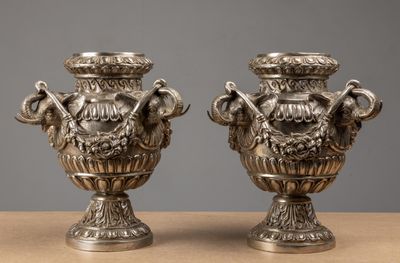 two silver vases sitting on top of a table next to each other