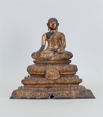 une statue antique de Bouddha en bronze, assise au sommet d'un tas de pierres