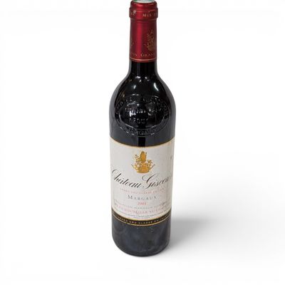 the bottle of red wine is sitting on a white surface