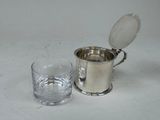 a silver cup and a glass sitting on a table