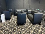a black couch and two black chairs in a room