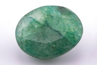 un gros plan d'une pierre verte sur une surface blanche
