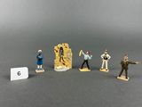 five figurines of people standing in front of a sign