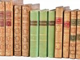 several old books are lined up in a row on a shelf