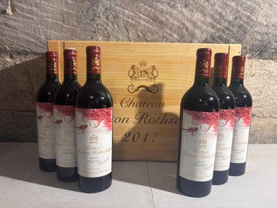 three bottles of red wine sit in front of a wooden box