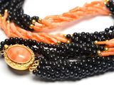 a picture of a necklace made of black and orange beads