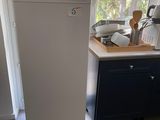 un réfrigérateur blanc dans une cuisine, près d'une fenêtre