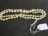 a white pearl necklace with a tag on a black surface