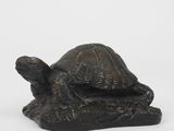 une statue représentant une tortue assise sur un rocher