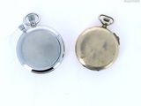 two silver pocket watches sitting next to each other on a white surface