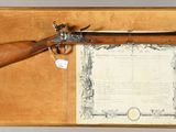 an old gun with a certificate in a case on a table
