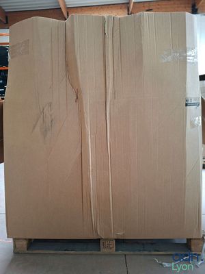 un grand carton posé sur une palette dans un entrepôt