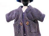 poupée vêtue d'un manteau violet et d'un chapeau bleu, posée sur un mannequin noir
