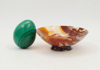 un bol en marbre et un œuf en marbre posés sur une surface blanche