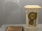 une horloge sous un dôme en verre, à côté d'une petite boîte
