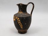a black and gold vase sitting on a white surface