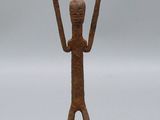 une petite figurine en bronze représentant un homme les mains levées