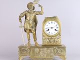a gold clock with a man standing next to it