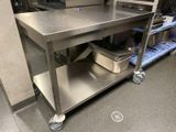 a stainless steel work table with a metal shelf on it