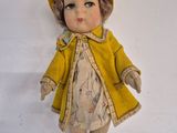 a doll that is wearing a yellow coat and hat