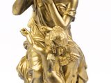 une statue antique en bronze représentant une femme avec un enfant et un chien