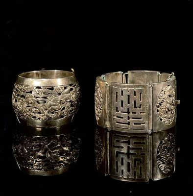 deux bracelets en argent posés sur une surface noire, sur fond noir