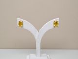 pair of yellow sapphire stud earrings on a white stand