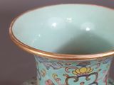 a blue vase with a gold rim sitting on a table