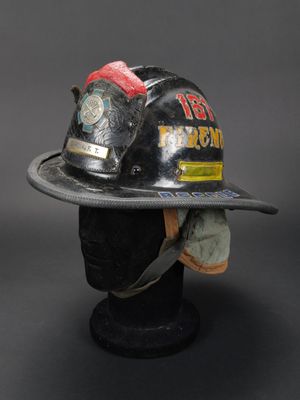 un casque de pompier posé sur la tête d'un mannequin coiffé d'un chapeau
