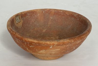 un petit bol marron posé sur une surface blanche