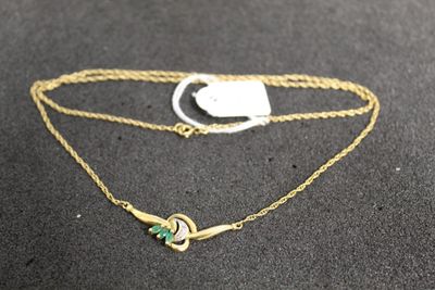 a close up of a gold chain with a green stone on it