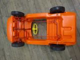 an orange toy car that is on a wooden floor
