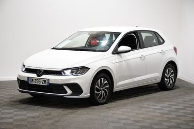 Une Volkswagen Polo blanche est garée dans une pièce dont le sol est à carreaux.