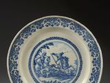 an image of a blue and white plate with a picture of a man on a boat