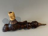 un porte-pipe en bois contenant une pipe, posé sur une table