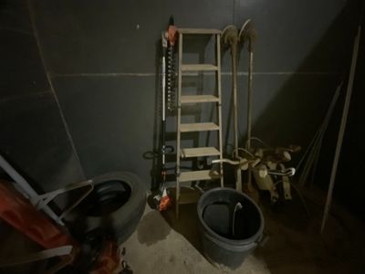 une pièce faiblement éclairée, avec une échelle, des seaux et des toilettes à l'intérieur