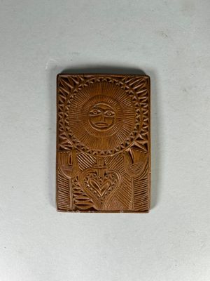 un gros plan sur une plaque en bois sur laquelle est représenté un soleil