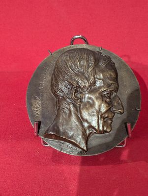 une plaque en bronze représentant le visage d'un homme sur un fond rouge