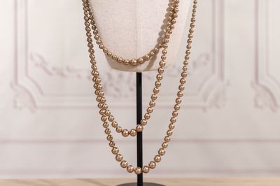 un gros plan d'un mannequin portant un collier de perles dorées