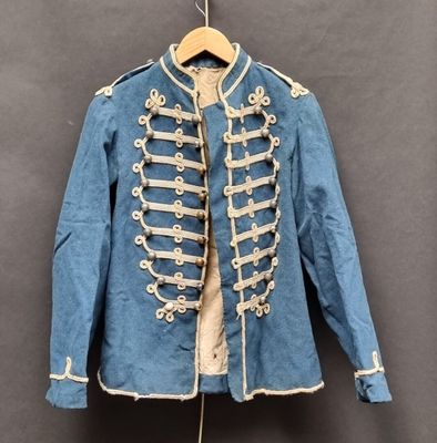 une vieille veste militaire bleue avec des boutons blancs, suspendue à un cintre